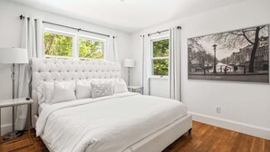 A bedroom with a large bed, two bedside tables, a nightstand, and a window with curtains. - BlackBerry Private home with jacuzzi yearlong (East Hampton)