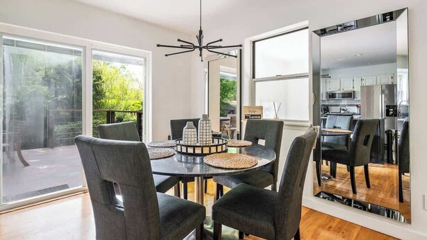 A dining area with a round table, six chairs, and a chandelier. - BlackBerry Private home with jacuzzi yearlong (East Hampton)