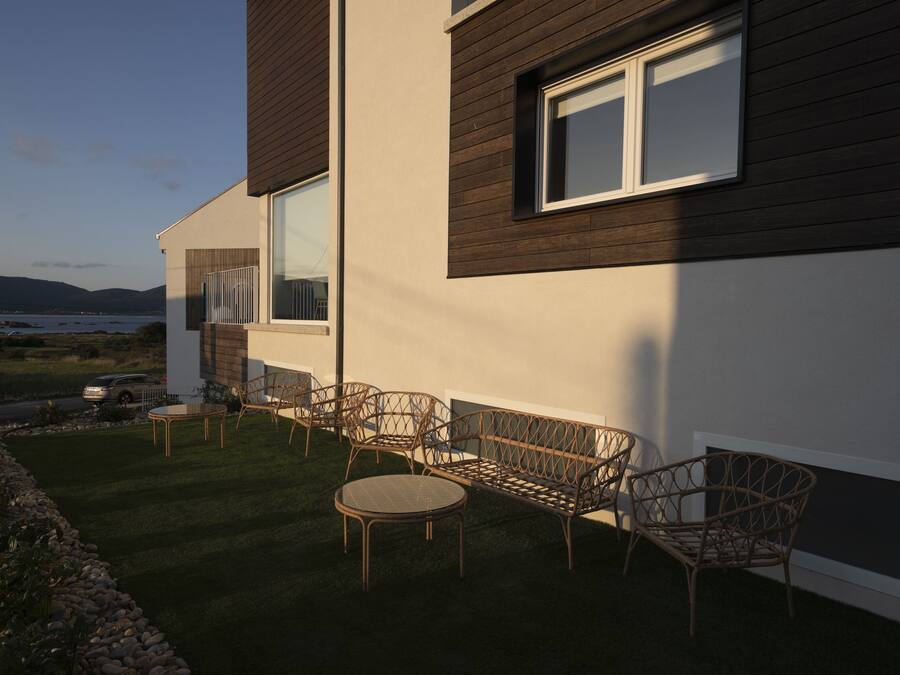 Una casa moderna con patio amoblado con muebles de mimbre y vista al mar.