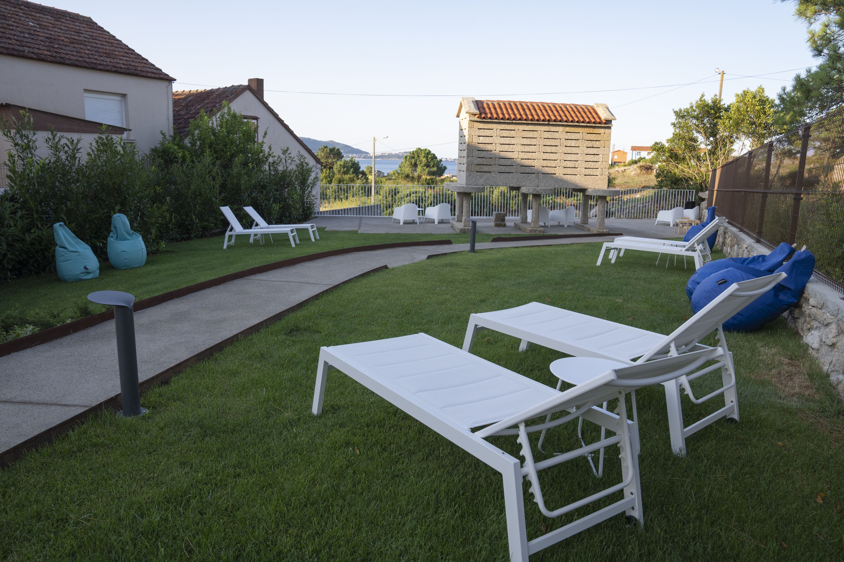 Een achtertuin met witte lounge stoelen, een kleine tafel en blauwe loungers.