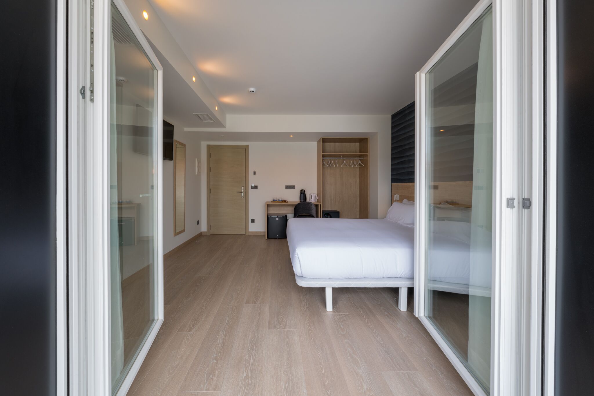 Una habitación de hotel moderna con una cama grande, un escritorio, un armario y una puerta corredera.