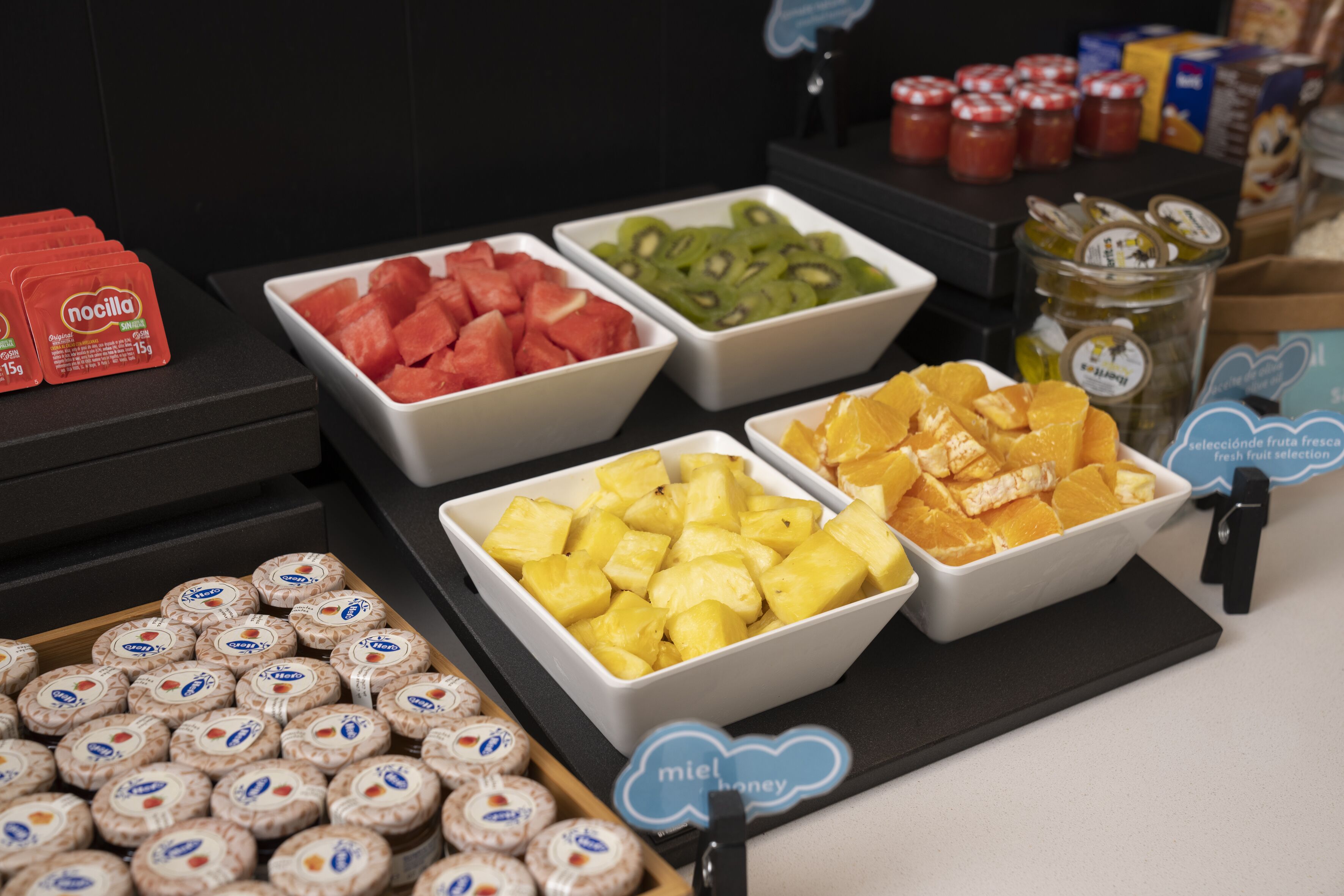 Un bufé con diversas frutas y aperitivos envasados.