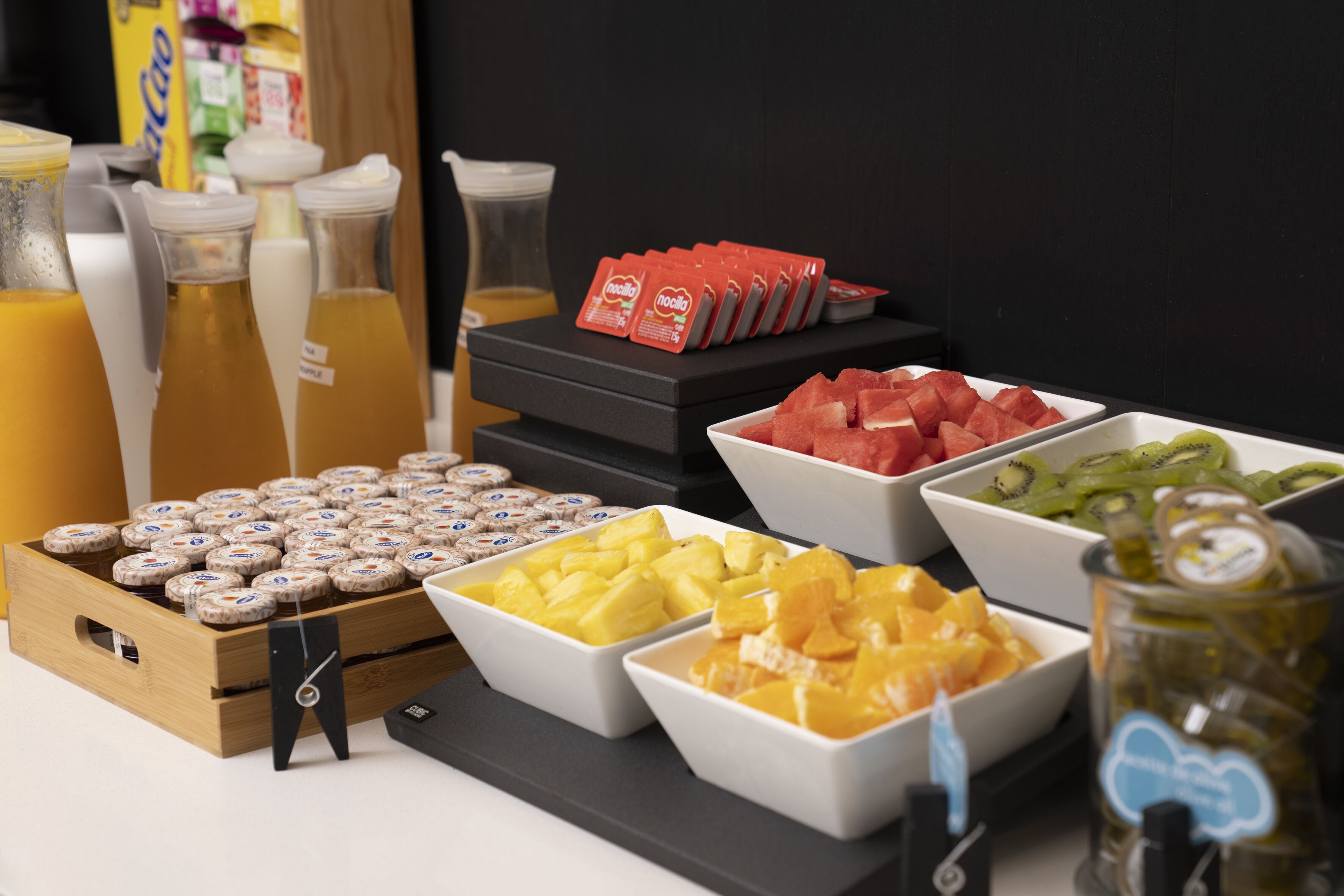 Un buffet de petit-déjeuner proposant une variété de fruits, de jus et de condiments.