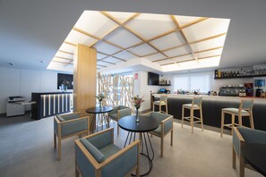 A modern bar area with seating, a reception desk, and a bar stocked with bottles. - Hotel Meiga do Mar & Spa (Carnota)
