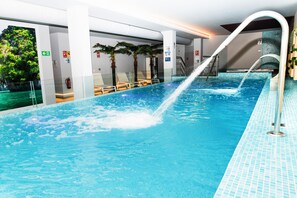 An indoor swimming pool with clear water, a water slide, and lounge chairs. - Hotel Meiga do Mar & Spa (Carnota)
