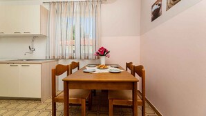 Une cuisine compacte avec une table à manger pour quatre personnes, une fenêtre avec des rideaux et un luminaire fixé au mur.