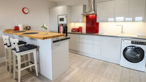Une cuisine moderne dotée d’un îlot central, d’appareils électroménagers intégrés et d’un lave-linge.
