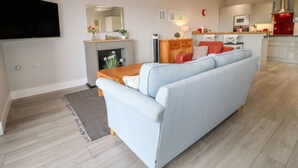 Un salon moderne avec un canapé, une cheminée et une cuisine en arrière-plan.