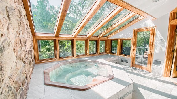 A spa area with a hot tub, large windows, and a stone wall. - Chateaux Dumont 2725 (Keystone)