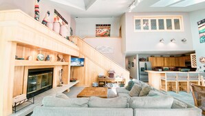 A spacious living room with a large sofa, a fireplace, and a kitchen area with wooden cabinets and a dining set. - Chateaux Dumont 2725 (Keystone)