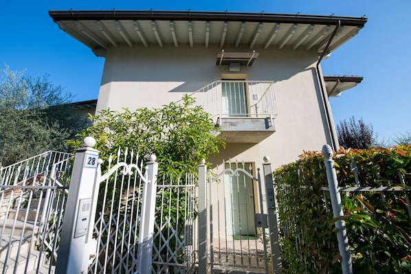A two-story house with a balcony, a gated entrance, and a number 28 sign on the gate. - Casa Isabella (Salò)