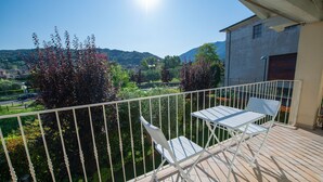 Un balcon doté de balustrades en métal blanc, ainsi que d’une table et de chaises.