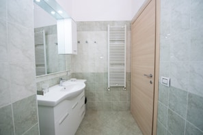 A modern bathroom with a double sink, a mirror, and a towel rack. - Casa Isabella (Salò)