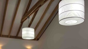 A bedroom with a bed, wooden beams, a wall-mounted TV, and two pendant lights. - El Cofre Secure and private gated home (Palmares)