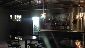 A bar area with tables and chairs, a bar counter, and hanging pendant lights. - El Cofre Secure and private gated home (Palmares)