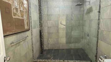A bathroom with a shower, toilet, and a tiled floor.