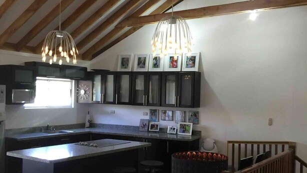 A modern kitchen with a central island, dark cabinets, and a wooden ceiling. - El Cofre Secure and private gated home (Palmares)