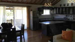 A spacious kitchen with a central island, a dining area with a table and chairs, and a living area with a sofa. - El Cofre Secure and private gated home (Palmares)
