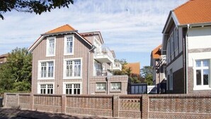 A multi-story residential building with a brick facade, multiple windows, and a balcony. - Wattkieker in the Lindenhof - centrally located with a classic design (Wangerooge)