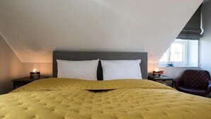 A bedroom with a large bed, two bedside tables, a chair, and a window. - Wattkieker in the Lindenhof - centrally located with a classic design (Wangerooge)