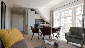 A modern living room with a sofa, a coffee table, and a dining area with chairs. - Wattkieker in the Lindenhof - centrally located with a classic design (Wangerooge)