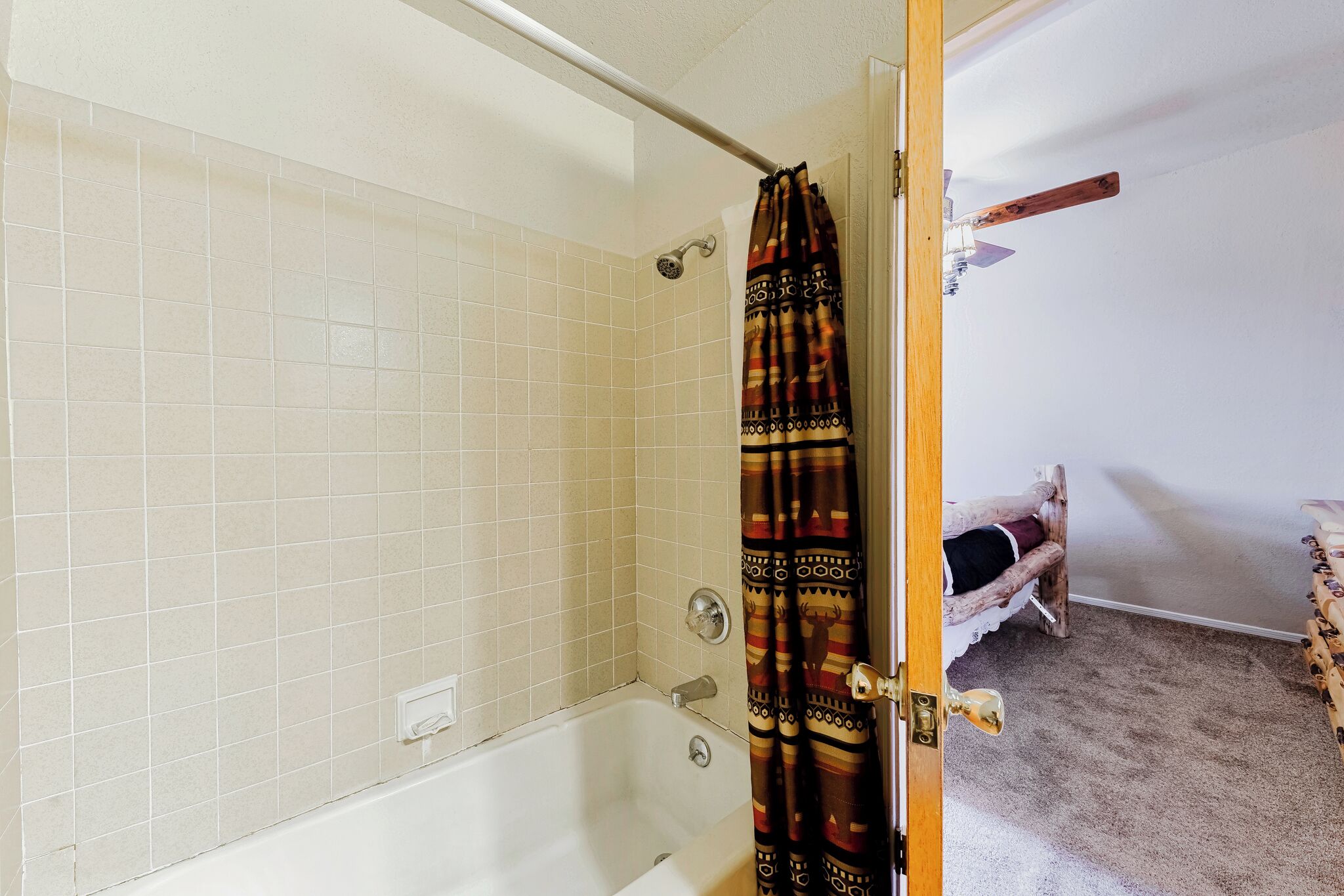 A bathroom with a bathtub, a shower curtain, and a wooden door.