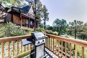 Eine Holterrasse mit Grill und einem Häuschen im Hintergrund.