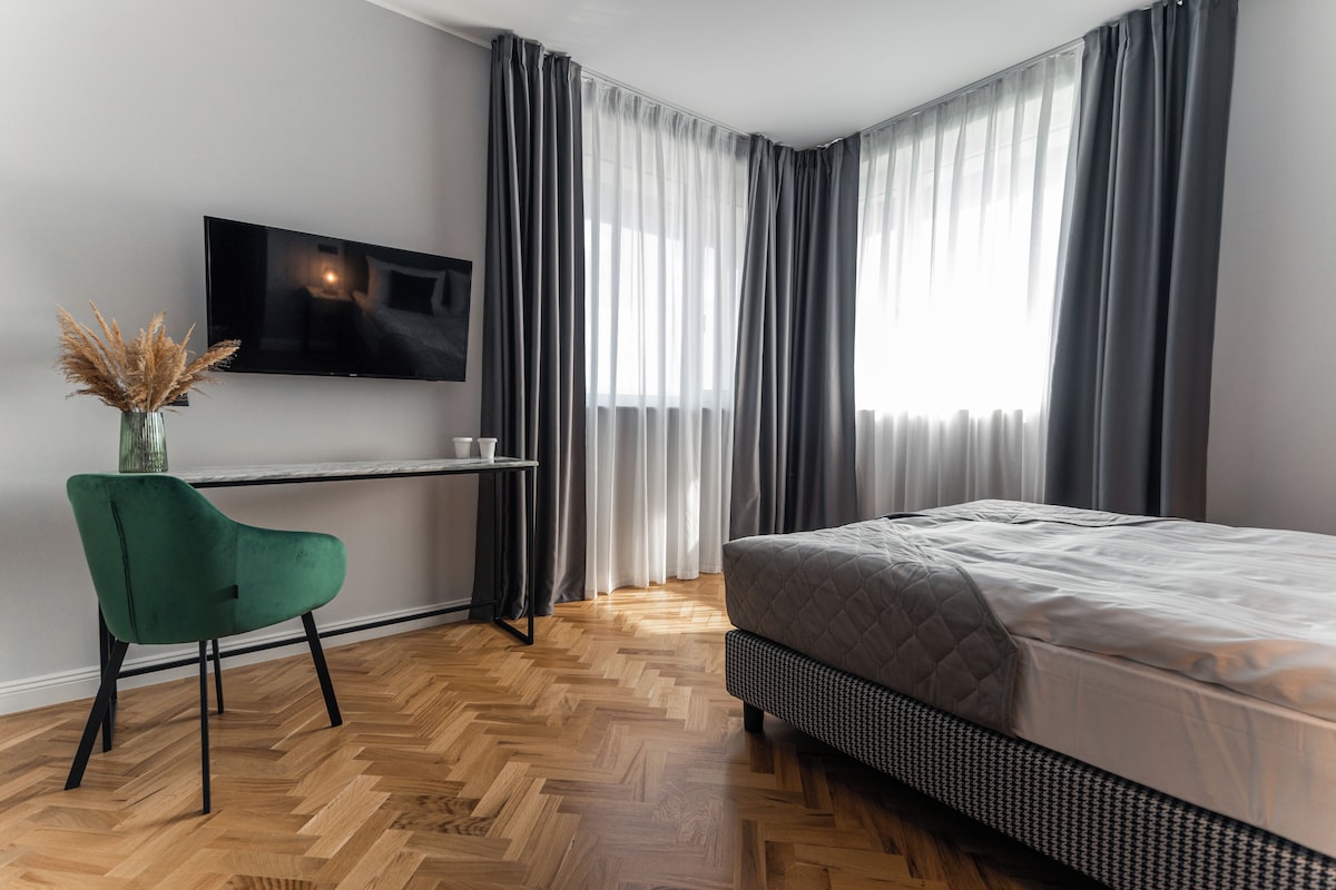 A modern bedroom with a bed, a desk, and a TV.