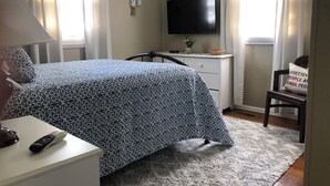 Makuuhuone, jossa on sänky, työpöytä, televisio ja tuoli.