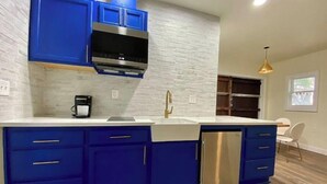 Cozinha com armários azuis, máquina de lavar louça de aço inoxidável e bancada branca.
