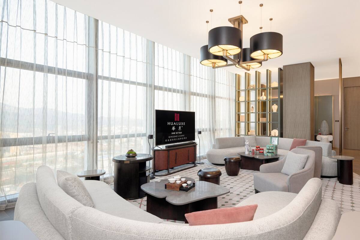A modern living room with a large TV, comfortable seating, and a city view.