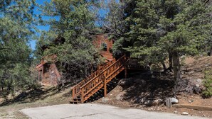 A wooden staircase leading to a cabin surrounded by trees. - Riverside House by Ruidoso Vacation Rentals (Ruidoso)