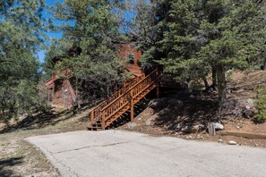 A wooden staircase leading to a cabin surrounded by trees. - Riverside House by Ruidoso Vacation Rentals (Ruidoso)