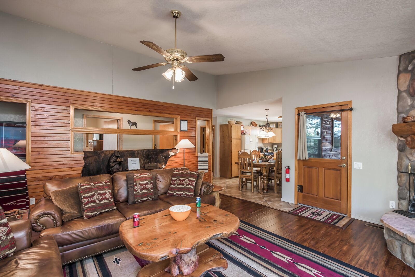 A cozy living room with a leather sofa, wooden coffee table, and a ceiling fan.