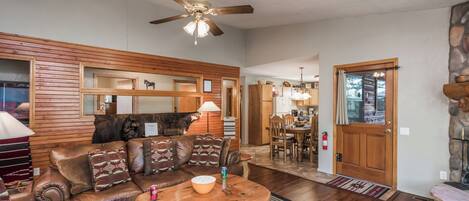 A cozy living room with a leather sofa, wooden coffee table, and a ceiling fan.