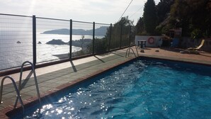 A swimming pool with a view of the sea, a fenced area, and a small table with a chair. - NUEVA Increíble casa con vistas al mar y piscina (Almuñécar)