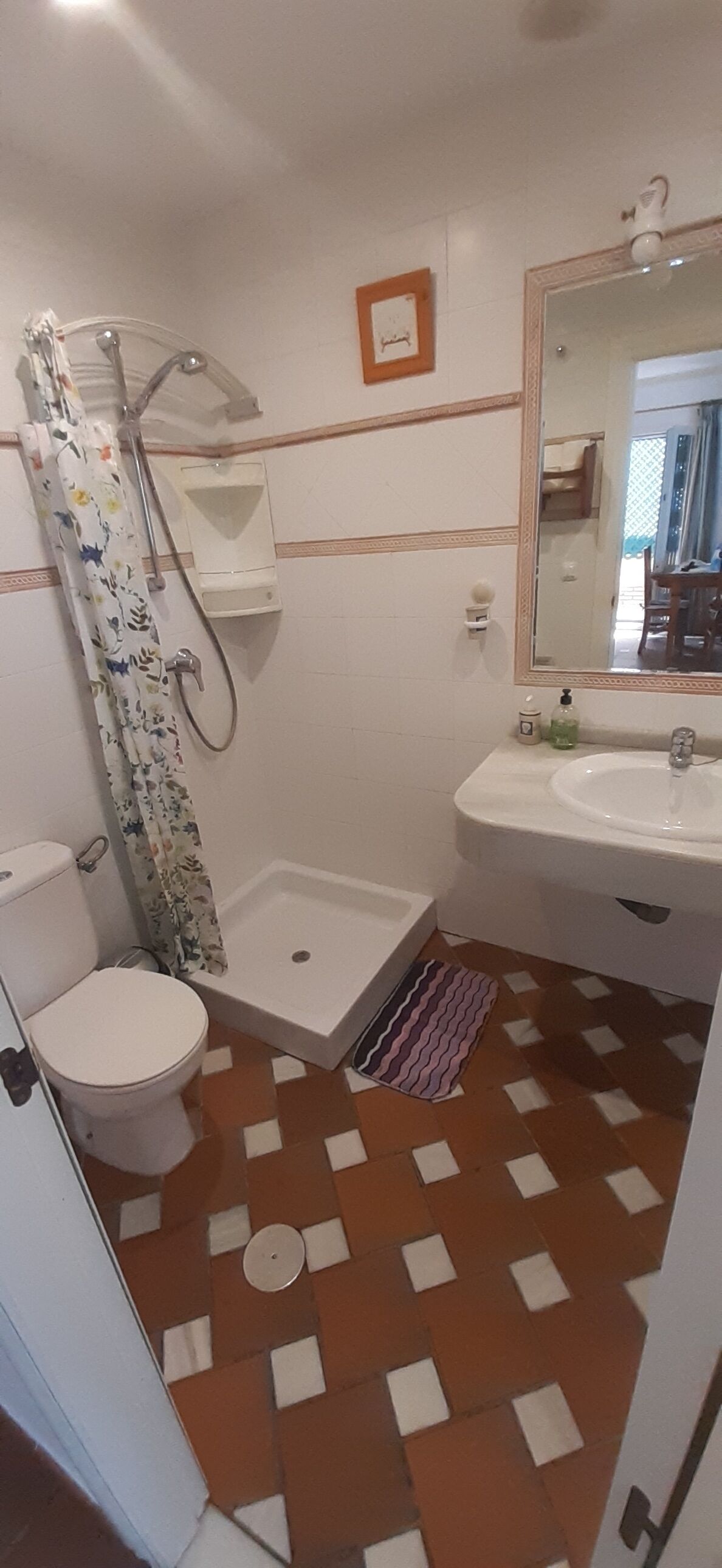 Une salle de bain équipée d’une douche, de toilettes, d’un lavabo et d’un miroir.