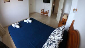 A bedroom with a bed, a TV, a chair, and a desk with a lamp. - NUEVA Increíble casa con vistas al mar y piscina (Almuñécar)