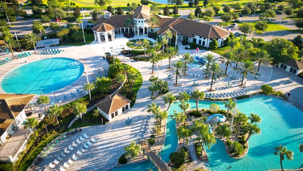 A resort with a large pool area, multiple lounge chairs, and a golf course in the background.
