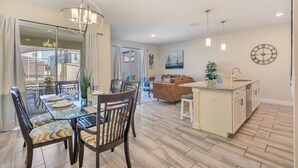A spacious living area with a dining table, chairs, a sofa, and a kitchen island.