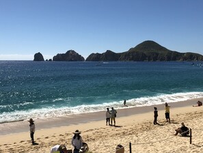 Une plage avec une eau d’un bleu limpide, des formations rocheuses et des gens qui se détendent sur le sable.