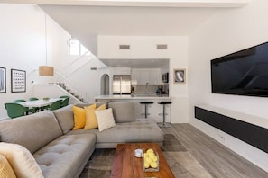 Ett modernt vardagsrum med en grå soffa, ett träbord och en platt-TV.