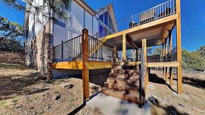 A two-story house with a wooden deck and a staircase leading to a balcony. - White Mountain Chateau by Ruidoso Vacation Rentals (Ruidoso)