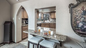 A kitchen with a marble countertop, wooden cabinets, and a framed floral artwork. - White Mountain Chateau by Ruidoso Vacation Rentals (Ruidoso)