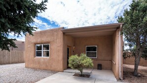 A single-story house with a flat roof, a small front porch, and a gravel driveway. - Casa Columbia by Kokopelli Property Management (Santa Fe)
