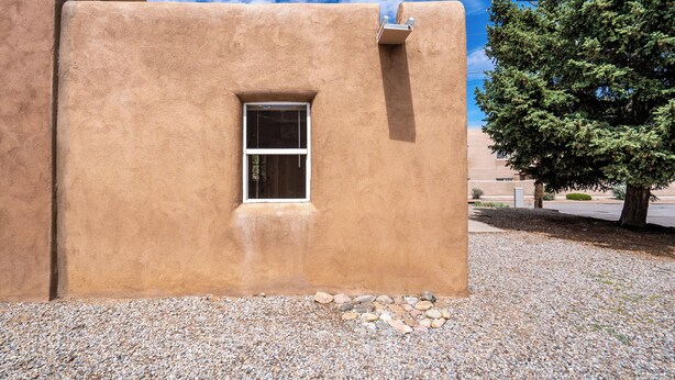 A stucco building with a small window and a white air conditioning unit. - Casa Columbia by Kokopelli Property Management (Santa Fe)