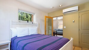 A bedroom with a bed, a window, an air conditioning unit, and a door. - Casa Columbia by Kokopelli Property Management (Santa Fe)