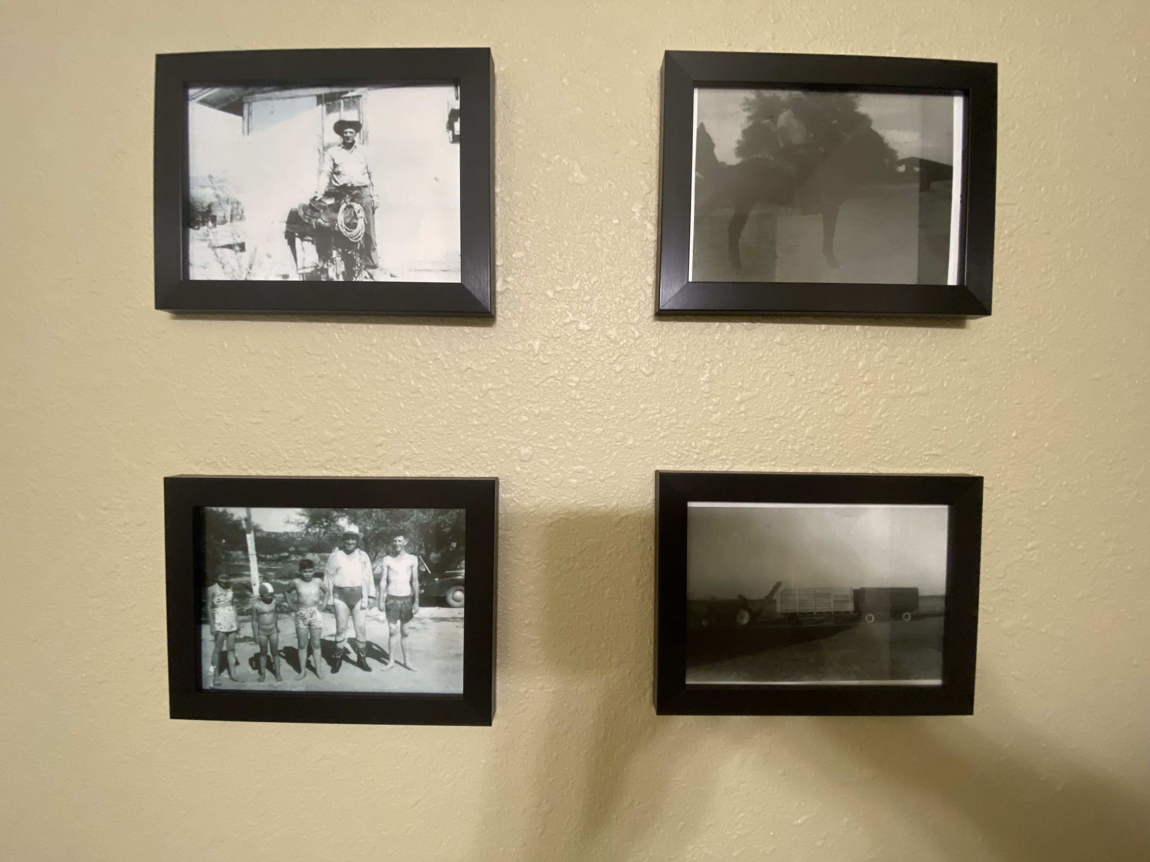 Vier zwart-wit foto's in lijsten aan een muur.