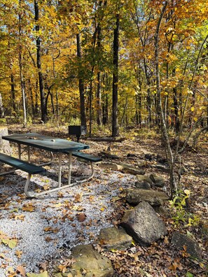 A picnic table in a forest with trees and rocks. - Cowboy Cabin is nestled in a little woodland village – playground, pond and more (Winslow)
