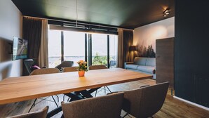 A modern dining area with a wooden table, six chairs, a potted plant, and a sofa. - Fortuna View - Sup. Apartment 'E' (Zell am See)